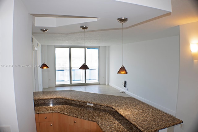 kitchen featuring dark stone counters, decorative light fixtures, and light tile patterned floors