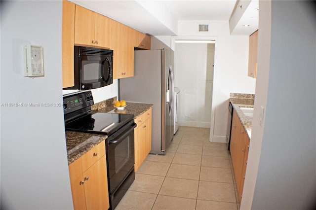 kitchen featuring light tile patterned flooring, dark stone countertops, and black appliances