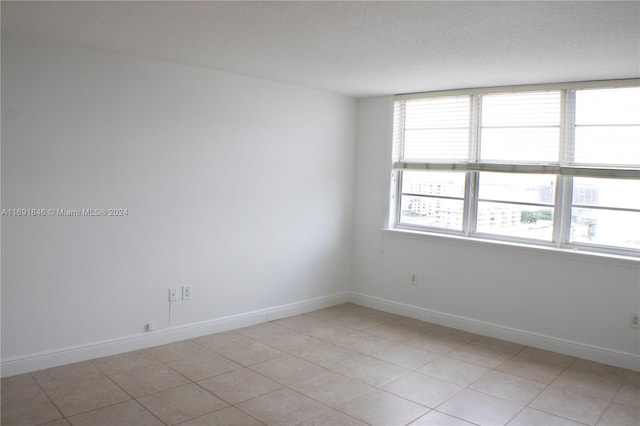 unfurnished room featuring a textured ceiling and light tile patterned flooring