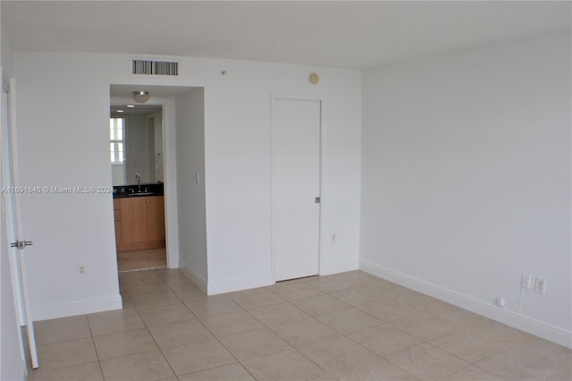 unfurnished room with sink and light tile patterned flooring