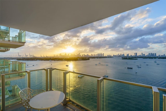 balcony at dusk featuring a water view