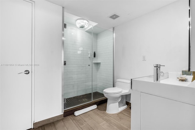 bathroom with hardwood / wood-style flooring, vanity, toilet, and walk in shower