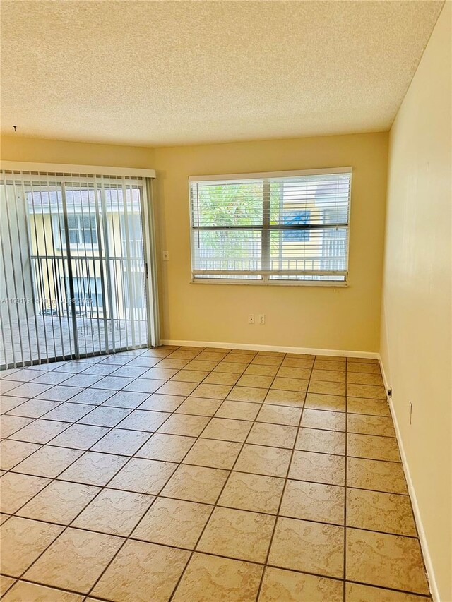 spare room featuring tile patterned flooring and a textured ceiling