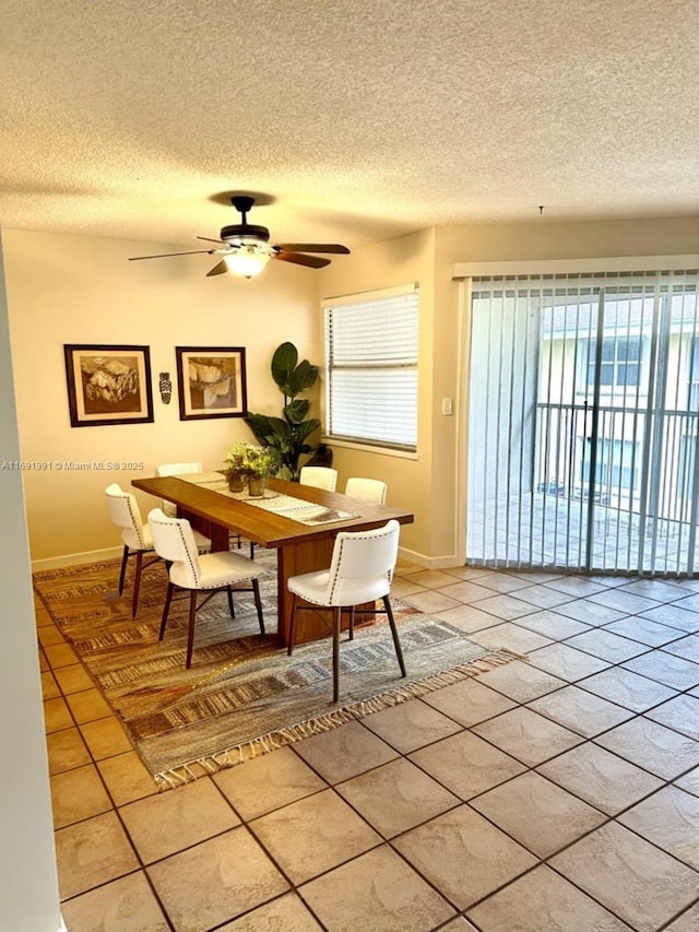 tiled dining space with ceiling fan and a textured ceiling