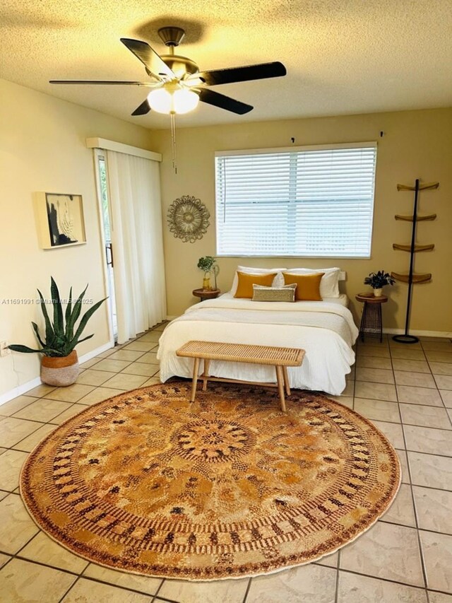 tiled bedroom featuring ceiling fan and a textured ceiling