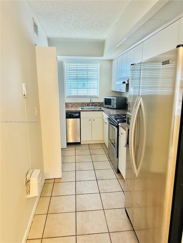 kitchen featuring sink, white cabinetry, a textured ceiling, light tile patterned floors, and appliances with stainless steel finishes