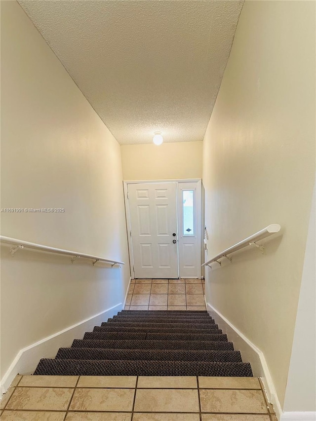 stairway with tile patterned flooring and a textured ceiling