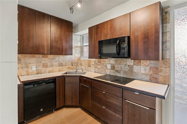 kitchen featuring a healthy amount of sunlight, light hardwood / wood-style floors, black appliances, and sink