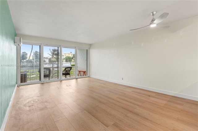 empty room with light hardwood / wood-style floors, ceiling fan, and a wall mounted air conditioner