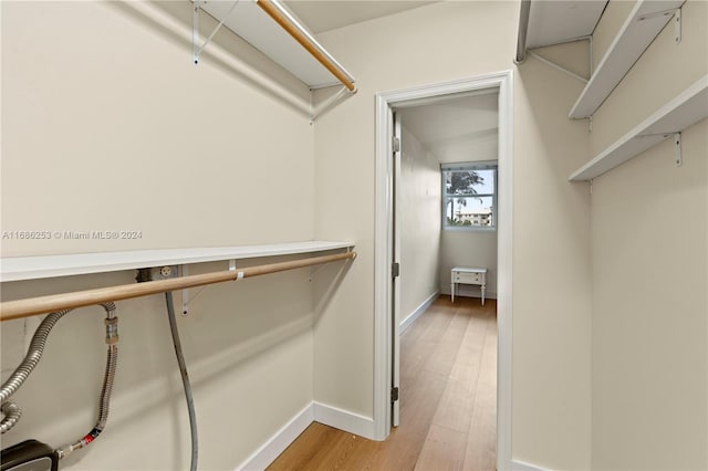 walk in closet with light hardwood / wood-style floors