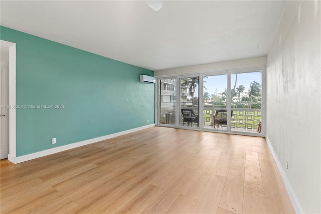 spare room with light hardwood / wood-style floors and an AC wall unit