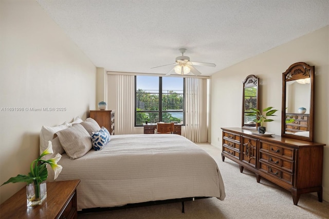 bedroom featuring ceiling fan, a wall of windows, light carpet, and a textured ceiling