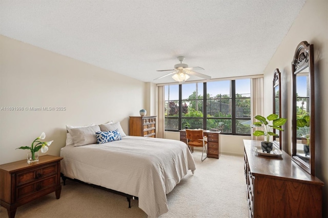 carpeted bedroom featuring ceiling fan and a textured ceiling