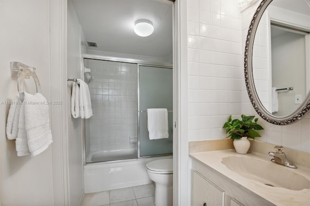 full bathroom with enclosed tub / shower combo, tile patterned flooring, vanity, tile walls, and toilet