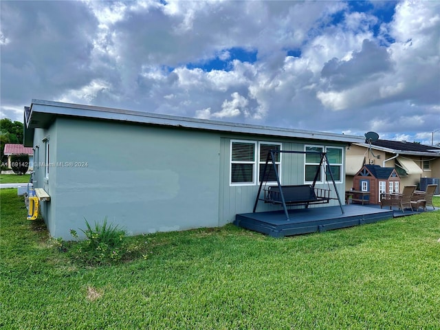 rear view of property featuring a wooden deck and a lawn