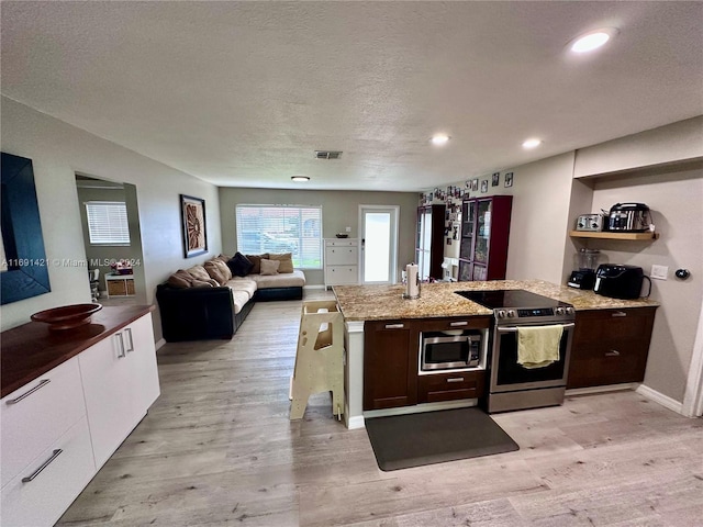 kitchen with stainless steel appliances, light hardwood / wood-style floors, white cabinets, a textured ceiling, and light stone countertops