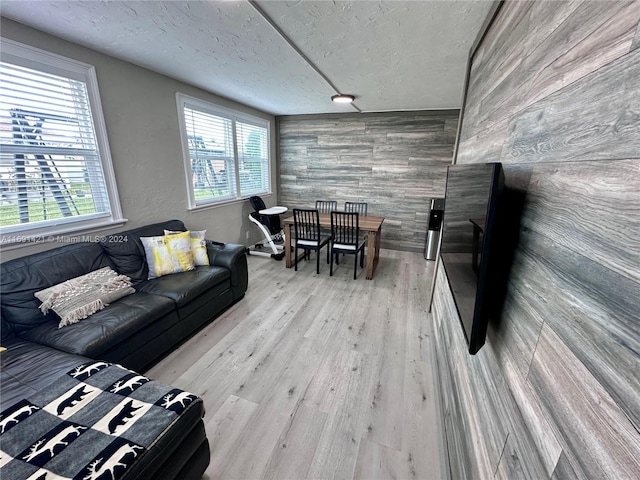 living room featuring wood walls, a wealth of natural light, a textured ceiling, and light hardwood / wood-style floors