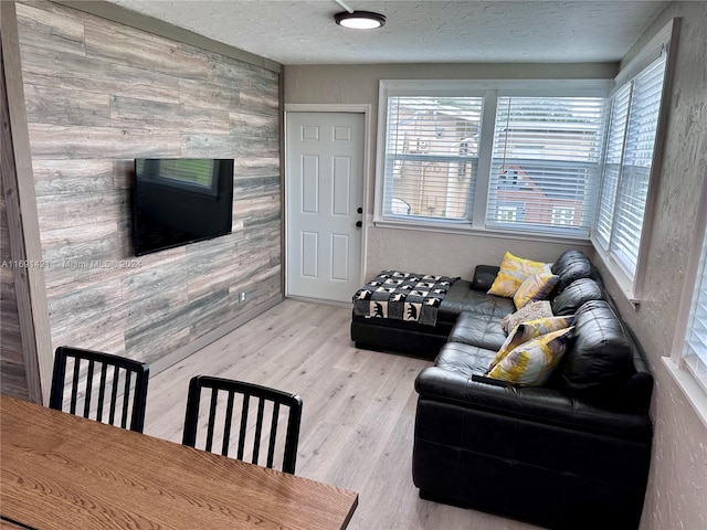 living room featuring wood walls, a textured ceiling, and wood-type flooring