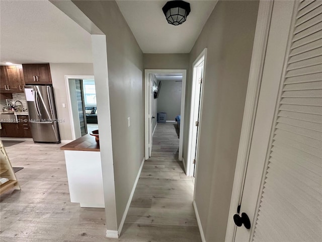 hallway with light hardwood / wood-style flooring and sink