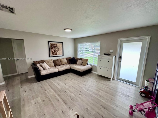 living room with light wood-type flooring and a textured ceiling