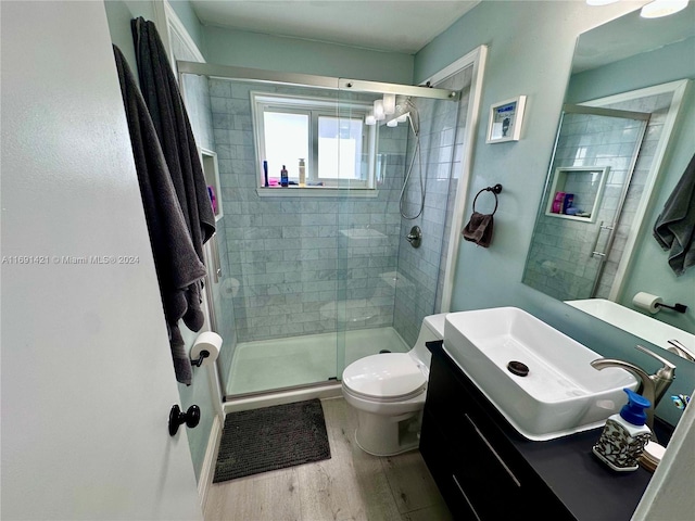 bathroom with walk in shower, vanity, wood-type flooring, and toilet