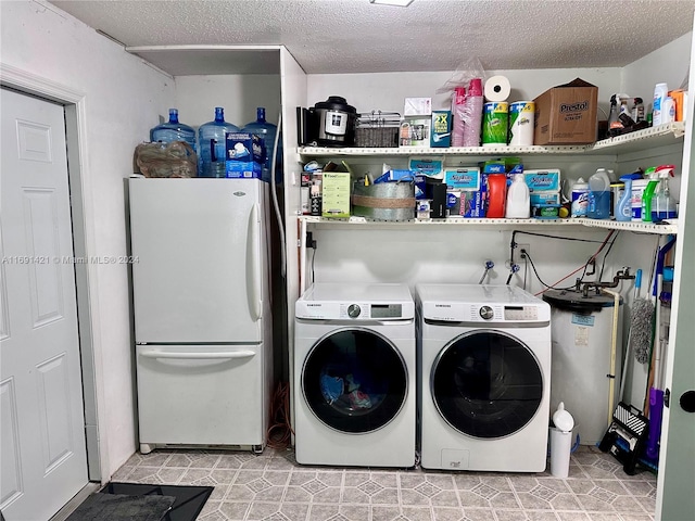 laundry area with water heater, washing machine and dryer, and a textured ceiling