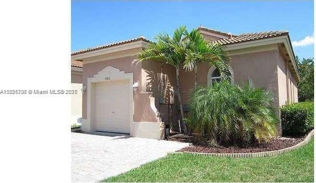 view of front of home with an attached garage, a tiled roof, and stucco siding