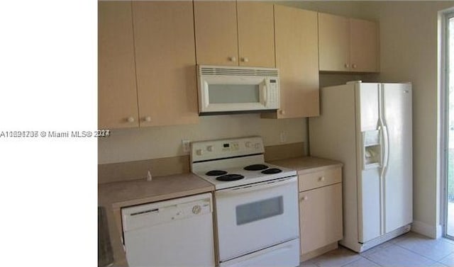 kitchen featuring light tile patterned flooring, white appliances, and cream cabinets