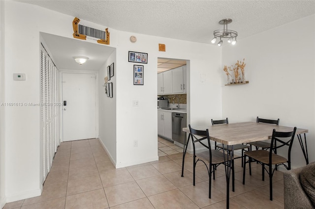 tiled dining room featuring a textured ceiling and sink