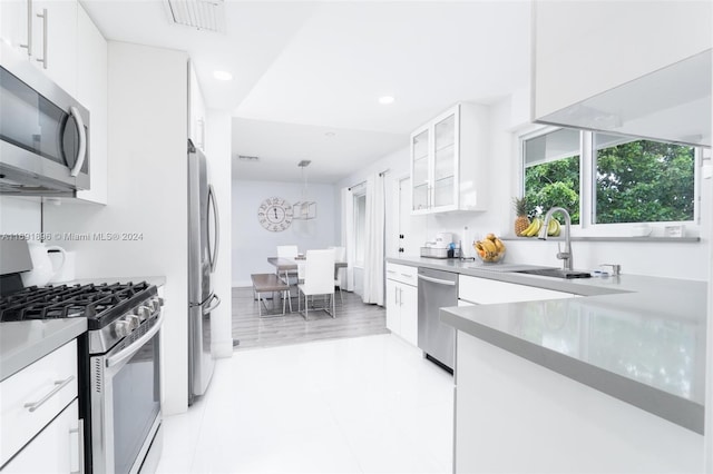 kitchen featuring white cabinets, sink, light wood-type flooring, and stainless steel appliances