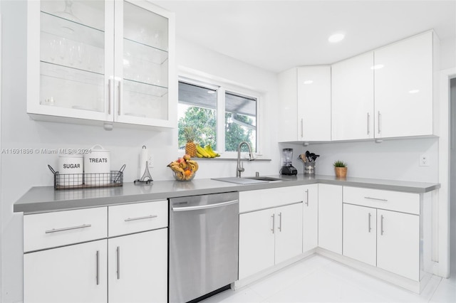 kitchen with dishwasher, light tile patterned floors, white cabinets, and sink