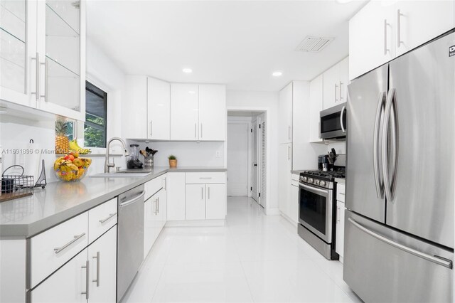 kitchen with light tile patterned flooring, white cabinetry, sink, and appliances with stainless steel finishes