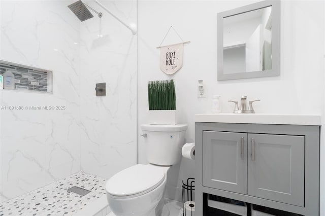 bathroom with tiled shower, vanity, and toilet