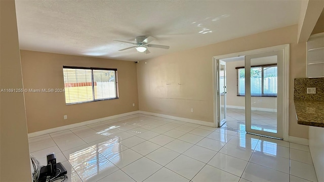 unfurnished room with ceiling fan, plenty of natural light, light tile patterned floors, and a textured ceiling