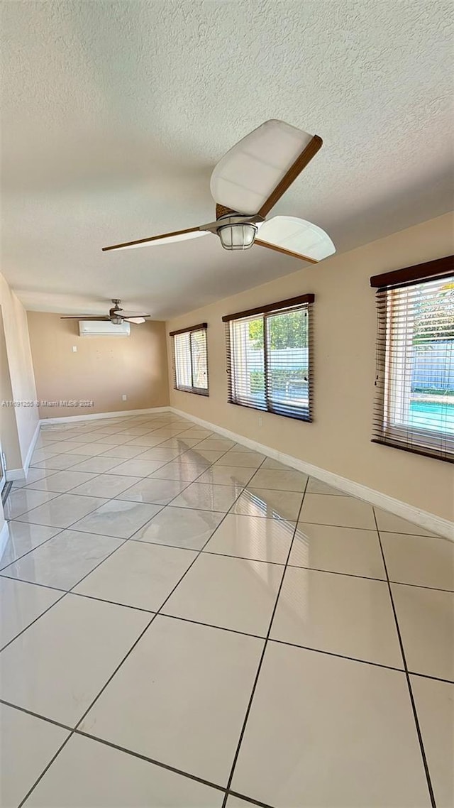 empty room with light tile patterned floors, a textured ceiling, and a wealth of natural light