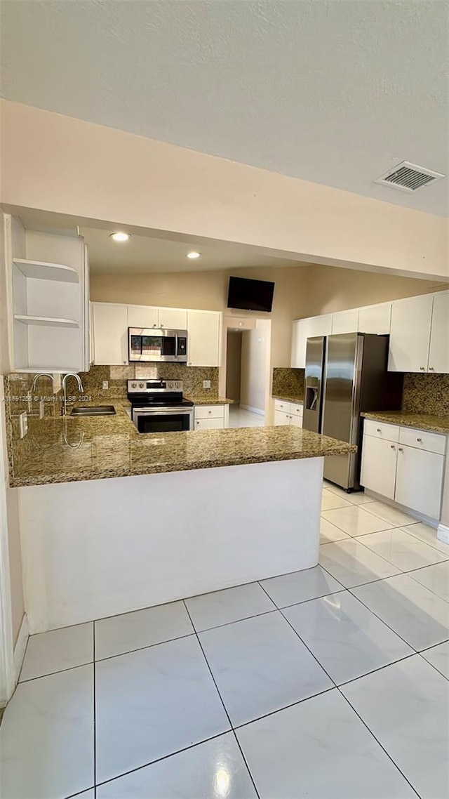 kitchen with sink, kitchen peninsula, decorative backsplash, appliances with stainless steel finishes, and white cabinetry