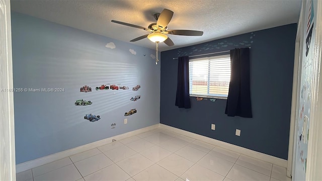 tiled spare room featuring a textured ceiling and ceiling fan