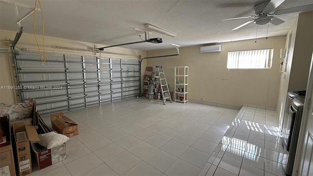 garage featuring a garage door opener, a wall unit AC, ceiling fan, and washing machine and clothes dryer