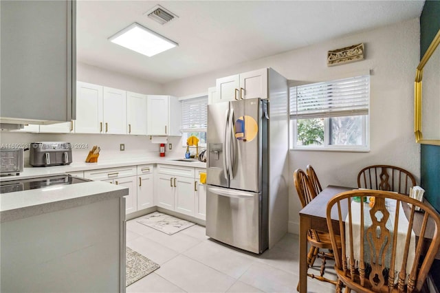 kitchen with light tile patterned floors, white cabinets, and stainless steel refrigerator with ice dispenser