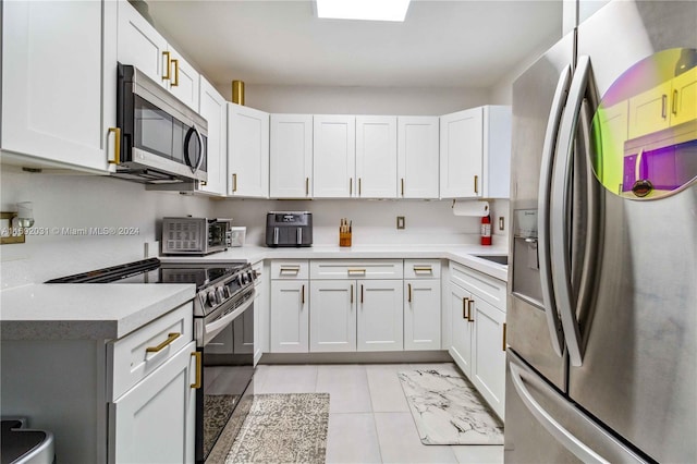 kitchen featuring white cabinets, light tile patterned flooring, and appliances with stainless steel finishes