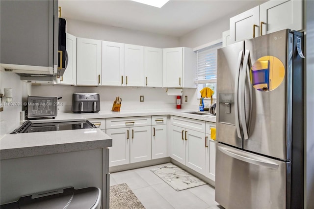 kitchen featuring white cabinetry, stainless steel fridge, sink, and light tile patterned floors