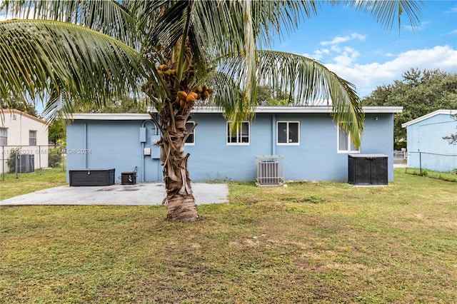 rear view of house with a lawn, cooling unit, and a patio