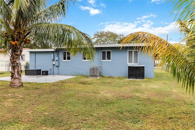 back of property with central air condition unit, a yard, and a patio