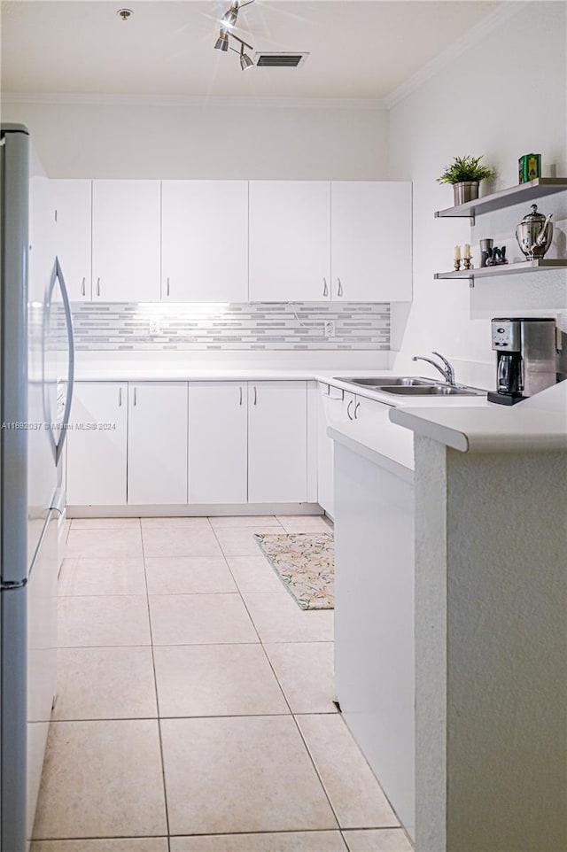 kitchen featuring white cabinets, crown molding, light tile patterned floors, white fridge, and kitchen peninsula