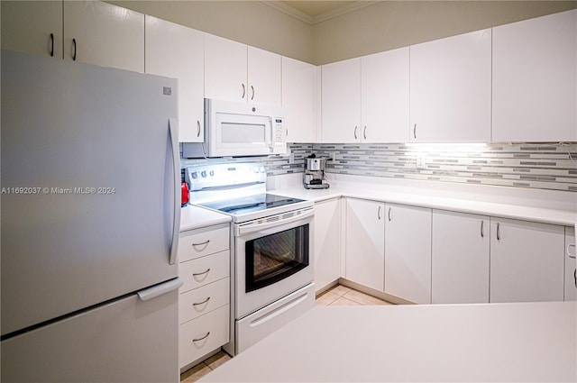 kitchen featuring white appliances, backsplash, light tile patterned floors, ornamental molding, and white cabinetry