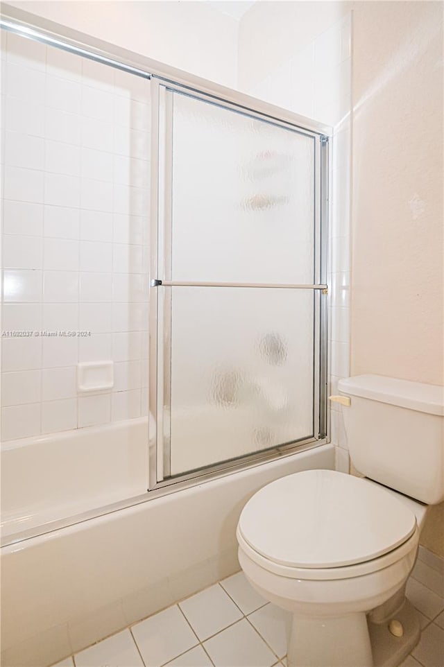 bathroom featuring tile patterned floors, toilet, and shower / bath combination with glass door