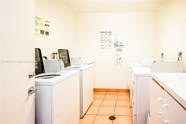 clothes washing area with washer and dryer and light tile patterned floors