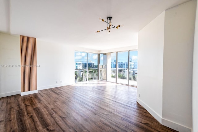 unfurnished room with dark hardwood / wood-style floors, an inviting chandelier, and floor to ceiling windows