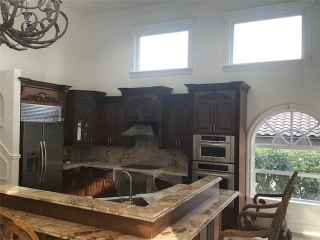 kitchen featuring backsplash, sink, dark brown cabinets, light stone counters, and stainless steel appliances