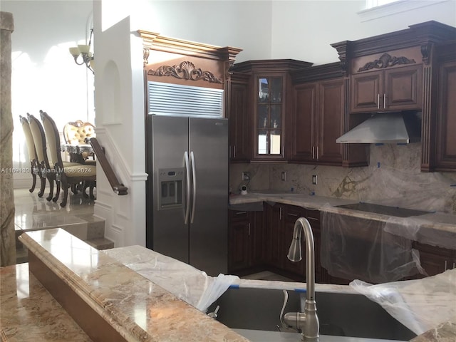 kitchen with stainless steel refrigerator with ice dispenser, backsplash, black electric stovetop, light stone counters, and dark brown cabinets